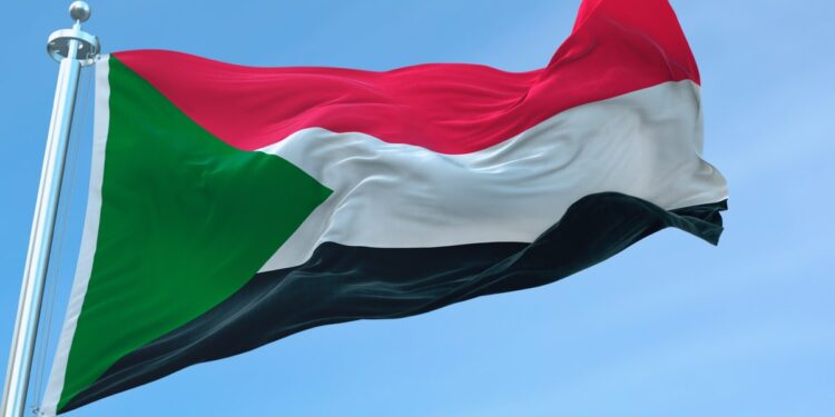 Palestinian flag flying atop a flagpole against a blue sky