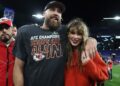 Travis Kelce smiles alongside Taylor Swift