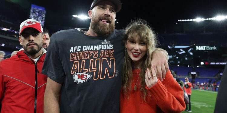 Travis Kelce smiles alongside Taylor Swift