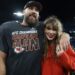 Travis Kelce smiles alongside Taylor Swift