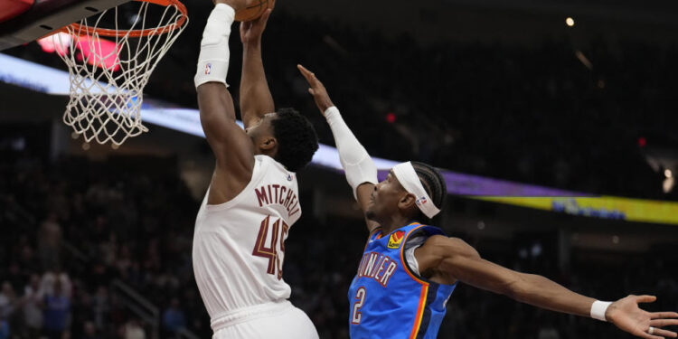 Cleveland Cavaliers guard Donovan Mitchell (45) goes up for a dunk in front of Oklahoma City Thunder guard Shai Gilgeous-Alexander (2) in the first half of an NBA basketball game, Wednesday, Jan. 8, 2025, in Cleveland. (AP Photo/Sue Ogrocki)