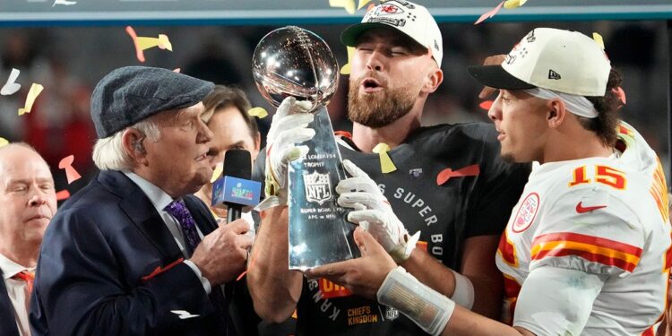 Travis Kelce and Patrick Mahomes pass the trophy