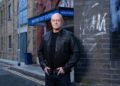 Ross Kemp in character on the EastEnders set, with Walford East Station behind him