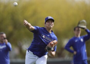 Dodgers star Shohei Ohtani throws the ball as he warms up with other pitchers and catchers