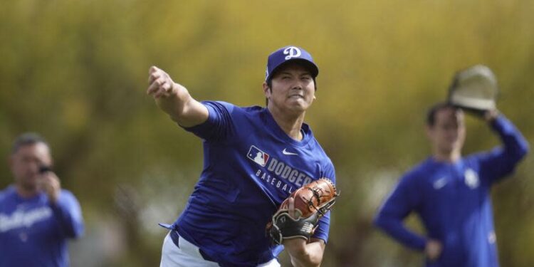 Dodgers star Shohei Ohtani throws the ball as he warms up with other pitchers and catchers