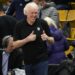 Television announcer Bill Walton acknowledges fans at an NCAA college basketball game.