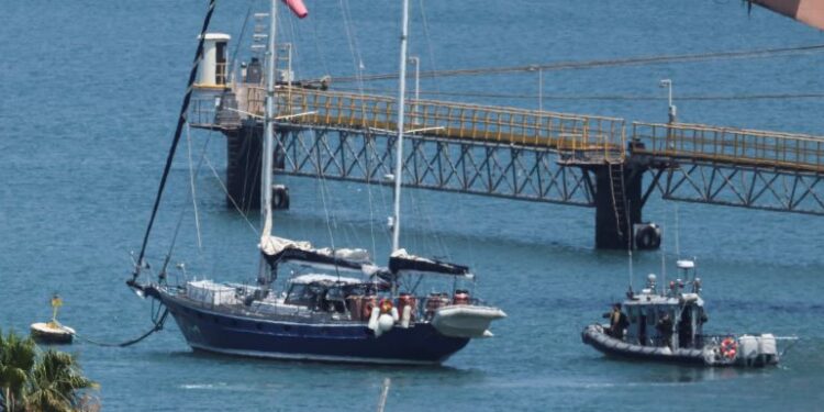 Gaza-bound British-flagged yacht "Madleen" is docked next to a military boat Ashdod port following a takeover by the Israeli army, in Ashdod, Israel, June 10, 2025 [Nir Elias/Reuters]