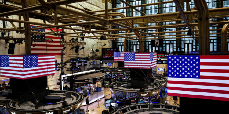 FILE PHOTO: American flags are displayed on screens on the floor at the New York Stock Exchange (NYSE) in New York City
