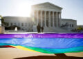 FILE PHOTO: Gay marriage supporters hold a gay rights flag in front of the U.S. Supreme Court before a hearing about gay m...