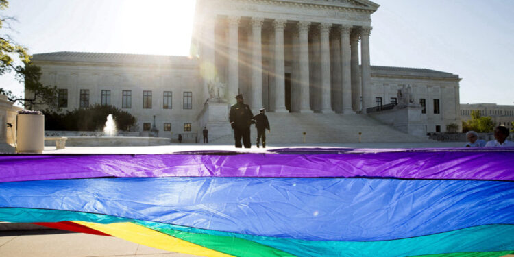 FILE PHOTO: Gay marriage supporters hold a gay rights flag in front of the U.S. Supreme Court before a hearing about gay m...