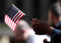 A citizenship candidate holds a flag during the U.S. Citizenship and Immigration Services (USCIS) naturalization ceremony ...