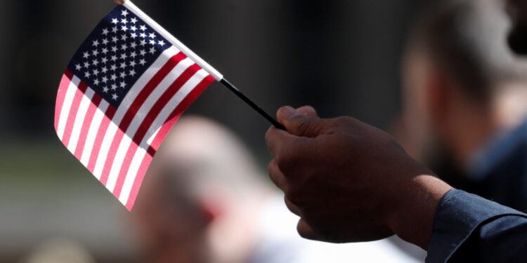 A citizenship candidate holds a flag during the U.S. Citizenship and Immigration Services (USCIS) naturalization ceremony ...