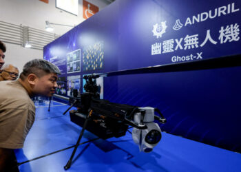 FILE PHOTO: Visitors look at the Ghost-X unmanned aerial vehicle developed by U.S. company Anduril