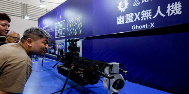 FILE PHOTO: Visitors look at the Ghost-X unmanned aerial vehicle developed by U.S. company Anduril