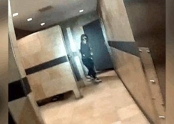 Suspect in black clothes and hoodie hold gun in restroom.