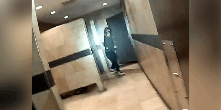 Suspect in black clothes and hoodie hold gun in restroom.