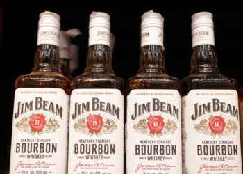Bottles of Jim Beam are displayed on a shelf in a supermarket