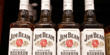 Bottles of Jim Beam are displayed on a shelf in a supermarket