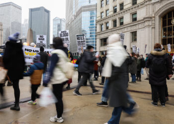 People walk past as demonstrators decry recent U.S. military actions...
