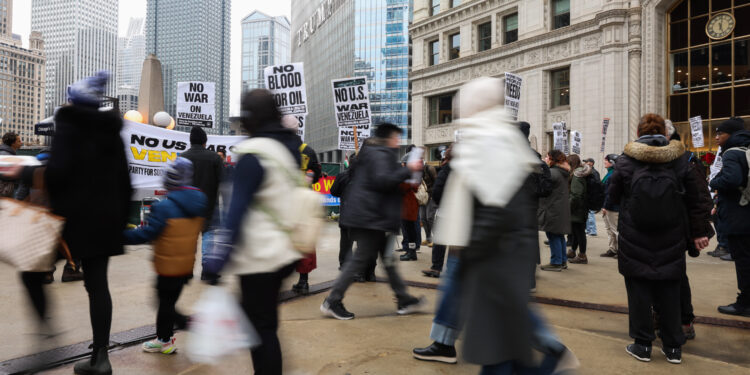 People walk past as demonstrators decry recent U.S. military actions...