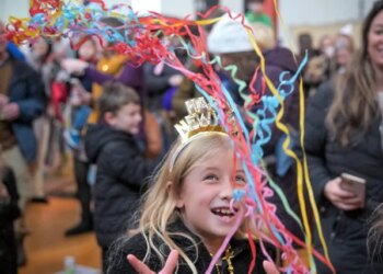 Maisie Holl, 8, of Ellicott City slingsconfetti above her head as the Noon Year's Eve ball drop count, a kid-friendly celebration to ring in 2026 completes at B&O Railroad Museum. (Karl Merton Ferron/Staff)