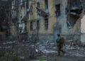 Ukrainian serviceman walks near an apartment building damaged by Russian military strike in the frontline town of Kostiant...