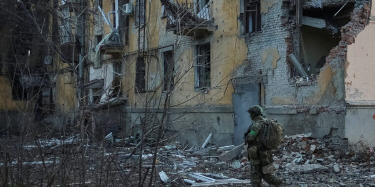 Ukrainian serviceman walks near an apartment building damaged by Russian military strike in the frontline town of Kostiant...