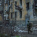 Ukrainian serviceman walks near an apartment building damaged by Russian military strike in the frontline town of Kostiant...