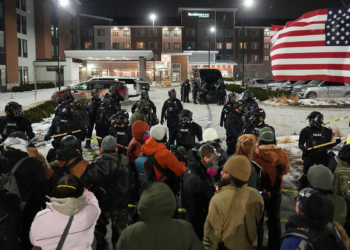 Demonstrators stand against law enforcement officers