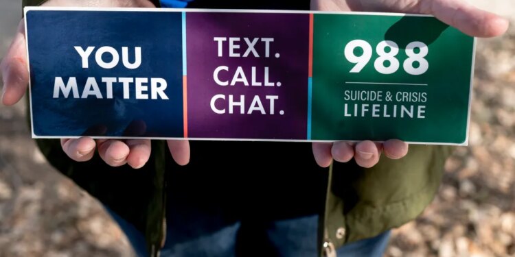 Hewitt holds a sticker for the new digits for Vibrant Emotional Health, the administer of the 988 Lifeline.