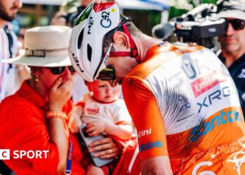 Cyclists ride past a kangaroo sign
