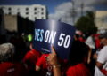 A protester holds a sign supporting Proposition 50
