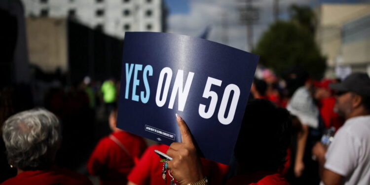 A protester holds a sign supporting Proposition 50