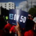 A protester holds a sign supporting Proposition 50