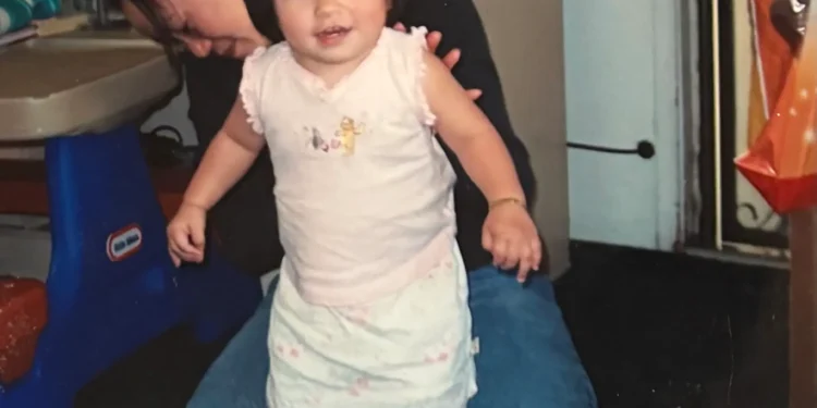 Mejicanos receives at-home physical therapy in 2004 with her physical therapist propping her up.