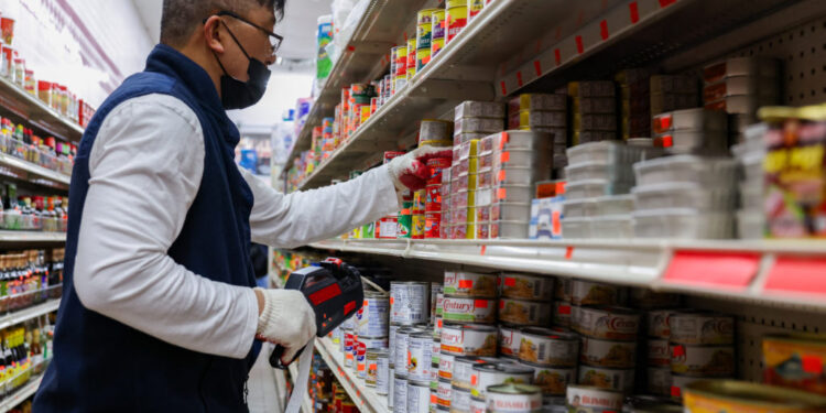 A Sun Vin Grocery employee adds price tags and stocks shelves in Chinatown in New York