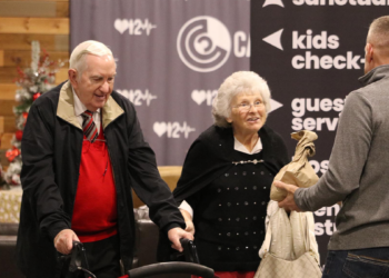 An elderly couple is assisted by a volunteer during a church community gathering
