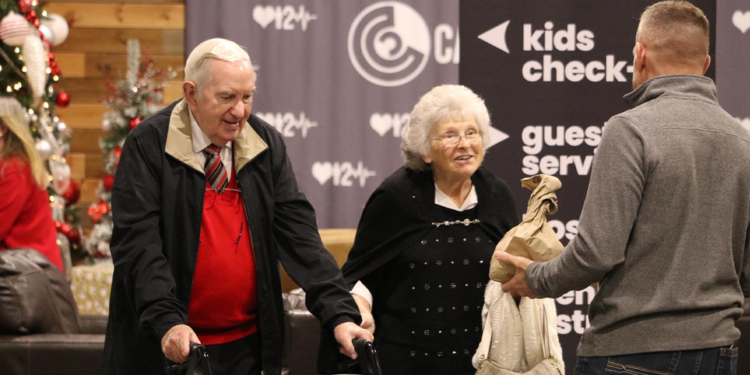 An elderly couple is assisted by a volunteer during a church community gathering