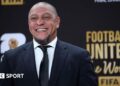 Roberto Carlos smiles for a photo while wearing a suit at the Fifa World Cup draw