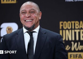 Roberto Carlos smiles for a photo while wearing a suit at the Fifa World Cup draw