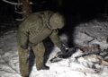 Russian soldier standing over drone wreckage in snow