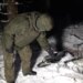 Russian soldier standing over drone wreckage in snow