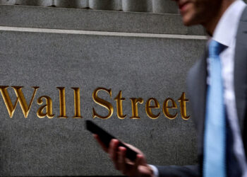 FILE PHOTO: A man walks on Wall St. outside the NYSE in New York