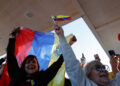 People wave Venezuelan flags and react to the news of U.S. strikes on Venezuela and capture of President Maduro, in Doral,...
