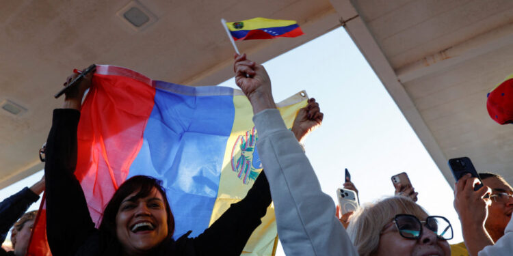 People wave Venezuelan flags and react to the news of U.S. strikes on Venezuela and capture of President Maduro, in Doral,...