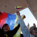 People wave Venezuelan flags and react to the news of U.S. strikes on Venezuela and capture of President Maduro, in Doral,...