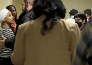 A security person holds back U.S. Rep. Ilhan Omar after a man disrupted a town hall meeting in Minneapolis