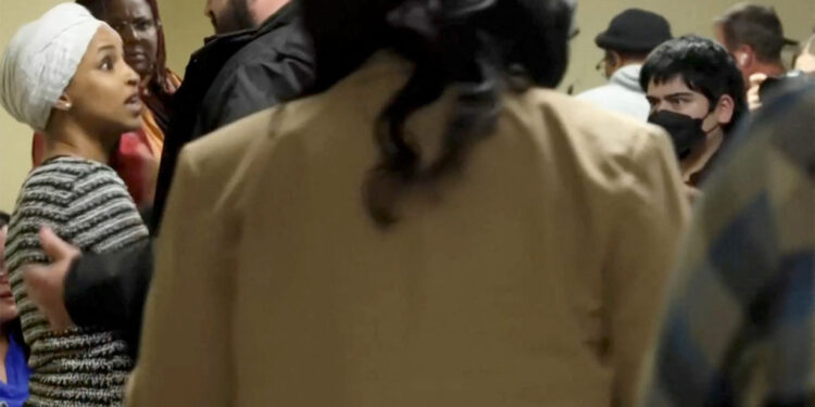 A security person holds back U.S. Rep. Ilhan Omar after a man disrupted a town hall meeting in Minneapolis