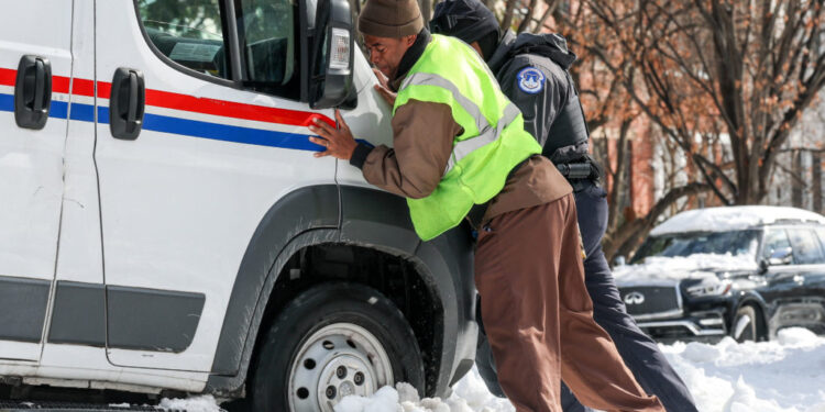 People help push a USPS truck out of snow and ice, two days after a winter storm in Washington