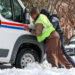People help push a USPS truck out of snow and ice, two days after a winter storm in Washington